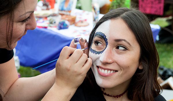 Girl getting face painted on Dia de los Muertos